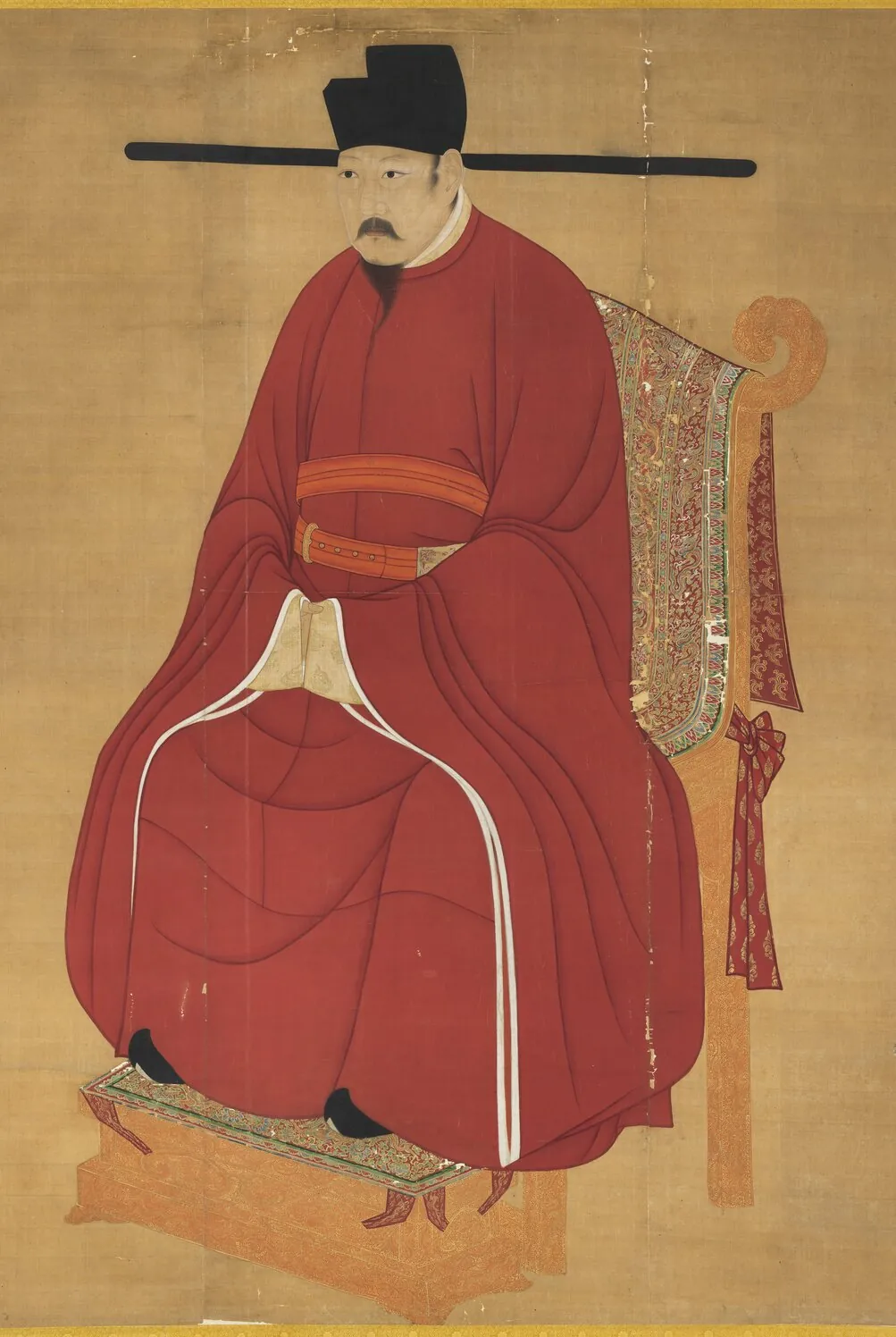 ภาพซ่งเหรินจง (宋仁宗 ซ่ง เหรินจง) ประทับนั่ง ภาพแขวนในพิพิธภัณฑ์พระราชวังไทเป ฮ่องเต้ที่เปาเจิ่งรับใช้ สวมหมวกปีกตรงยาวแบบซ่ง
