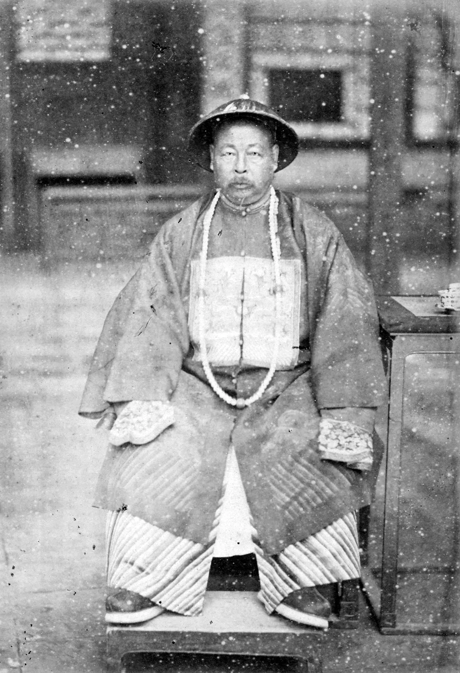 ภาพถ่ายขาวดำจั่วจงถัง 左宗棠 ปี 1875 แม่ทัพแซ่จั่วสมัยราชวงศ์ชิง นั่งในชุดขุนนาง สวมหมวกปีกกลม คล้องสร้อยลูกประคำยาว