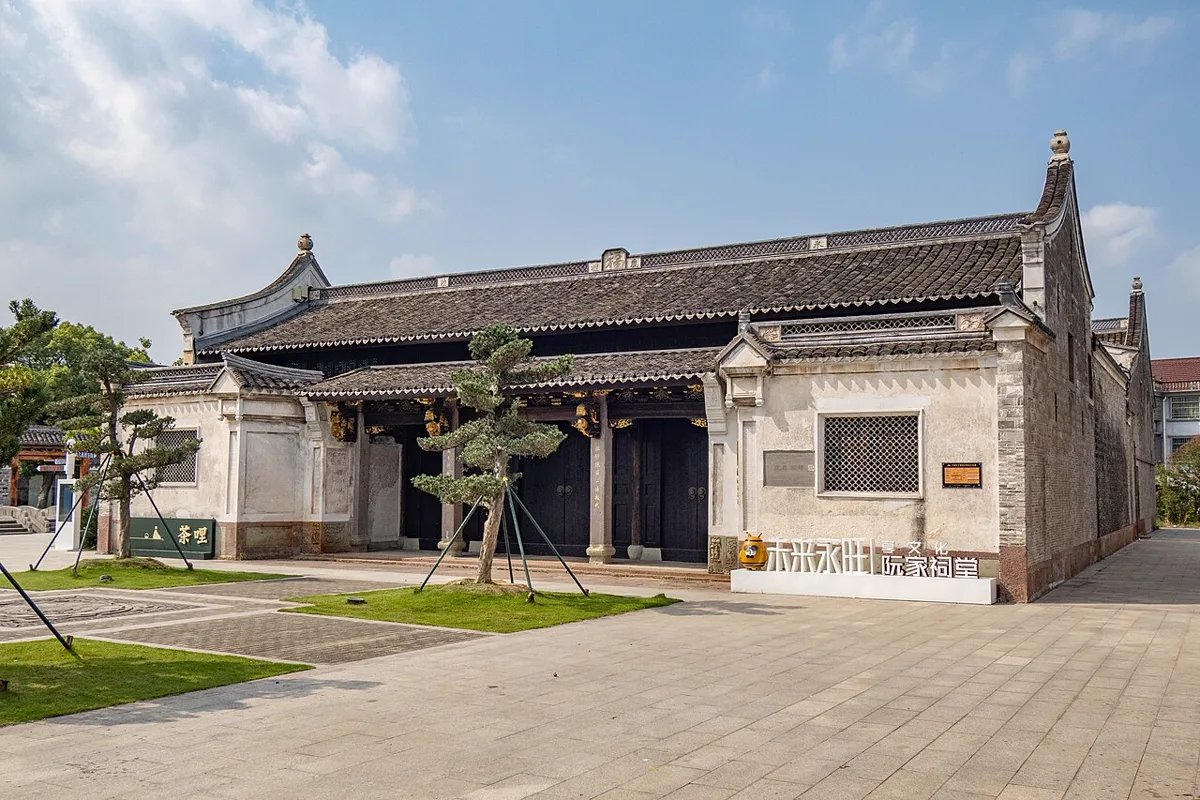 ศาลบรรพชนตระกูลหร่วน แซ่ง้วง 阮氏宗祠 หมู่บ้านหย่งวั่ง เจิ้นไห่ หนิงโป หลังคากระเบื้องสีเทา ผนังปูนขาว ประตูไม้สีดำ ลานหน้ามีต้นสนดัด