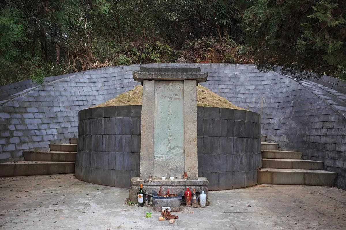 สุสานซินชี่จี๋ 辛弃疾 กวีแซ่ซิน ที่อำเภอเยียนซาน เจียงซี เนินดินทรงกลมล้อมกำแพงหินสีเทา ป้ายหลุมศพหินมีขวดเหล้าและเครื่องเซ่นวางอยู่หน้าป้าย