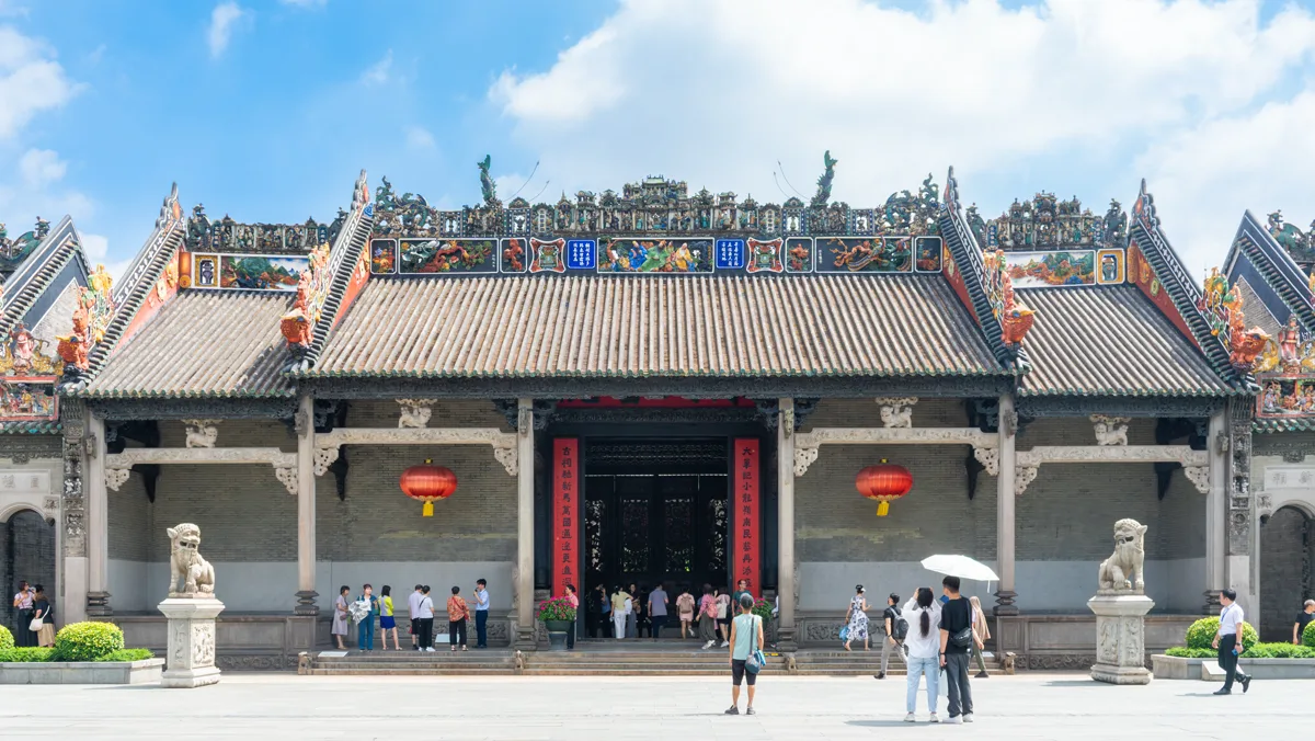 ด้านหน้าหอบรรพชนแซ่เฉิน 陈家祠 ที่กว่างโจว หลังคาประดับรูปปั้นสีสด มีโคมแดงและสิงโตหินคู่หน้าทางเข้า