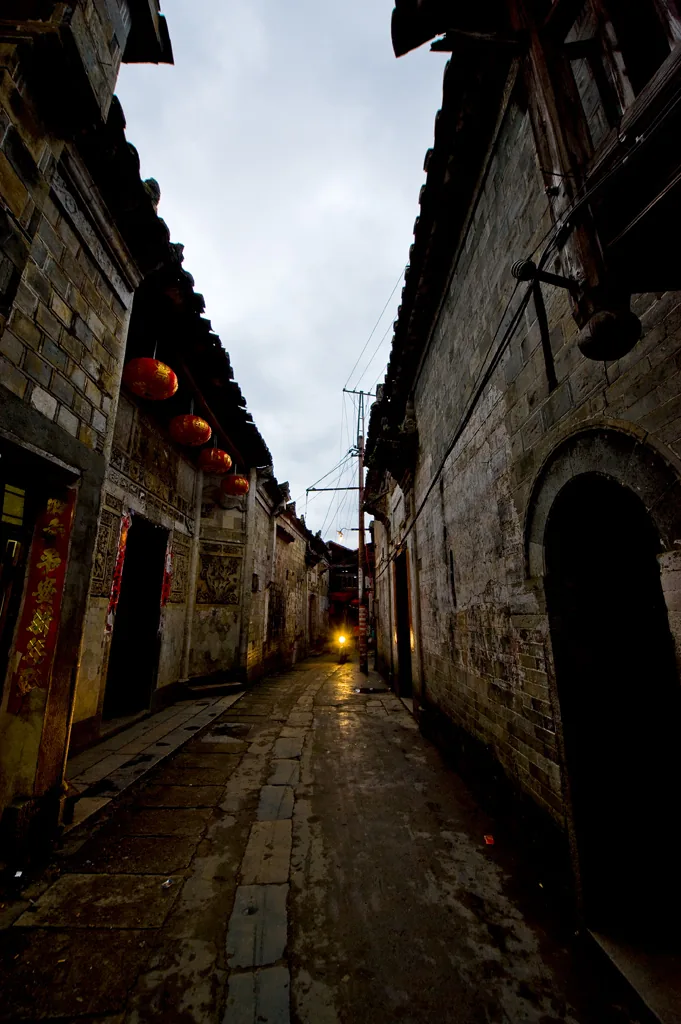 ตรอกหินในเมืองโบราณ บ้านไม้และกำแพงอิฐเก่าสองข้างทาง
