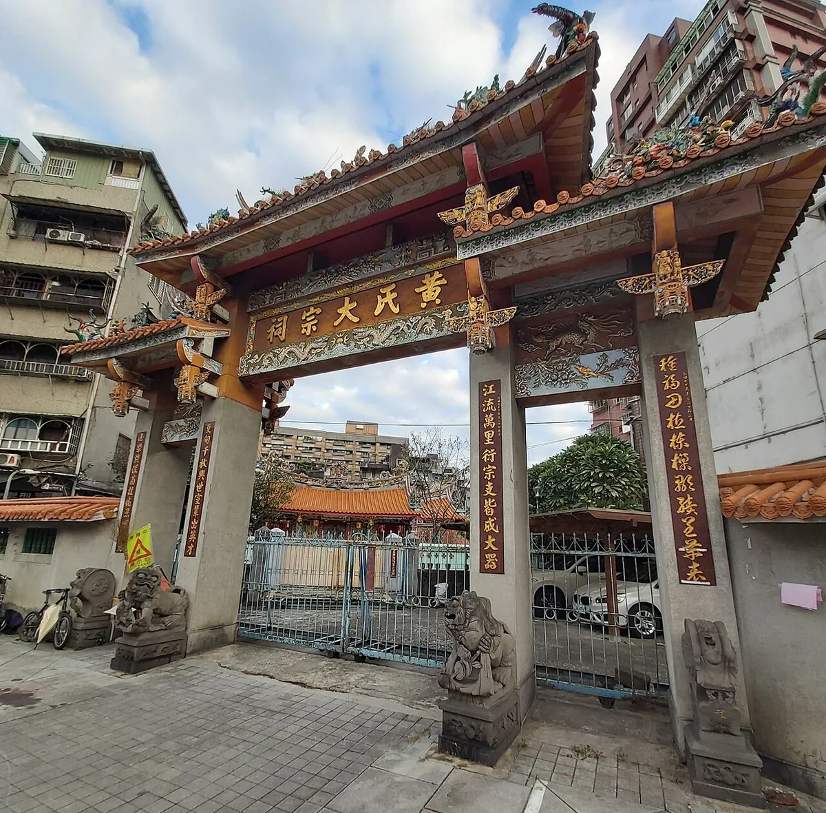 ซุ้มประตูศาลบรรพชน มีป้าย 黃氏大宗祠 และคู่กลอนบนเสา